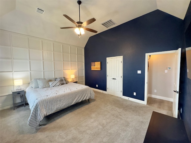 carpeted bedroom with ceiling fan and high vaulted ceiling