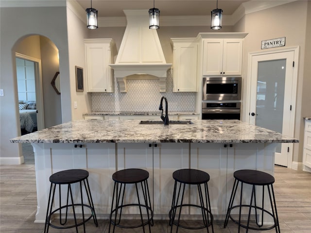 kitchen featuring a spacious island, white cabinets, light stone counters, and stainless steel appliances