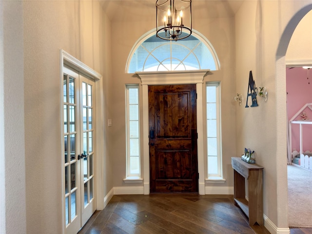 foyer entrance with dark wood-type flooring, french doors, and a notable chandelier