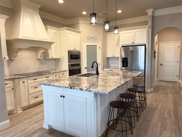 kitchen with sink, white cabinets, appliances with stainless steel finishes, and a kitchen island with sink