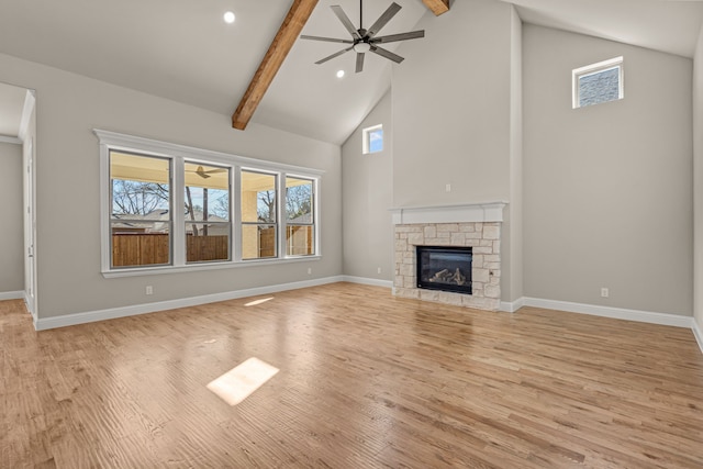 unfurnished living room with high vaulted ceiling, a fireplace, beamed ceiling, ceiling fan, and light hardwood / wood-style floors