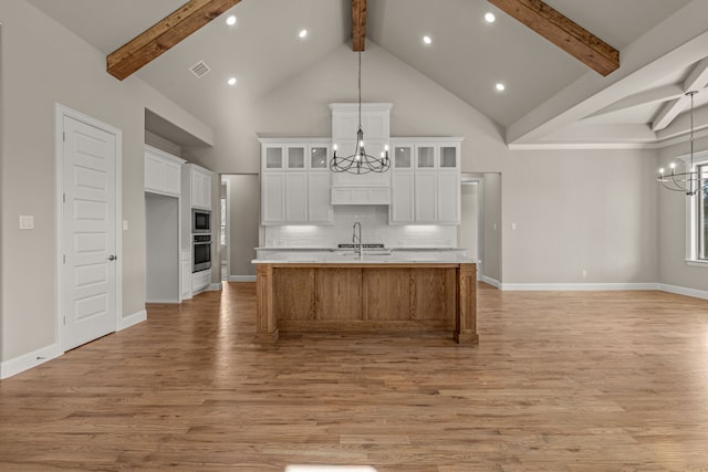 kitchen with white cabinets, a large island, oven, and a notable chandelier