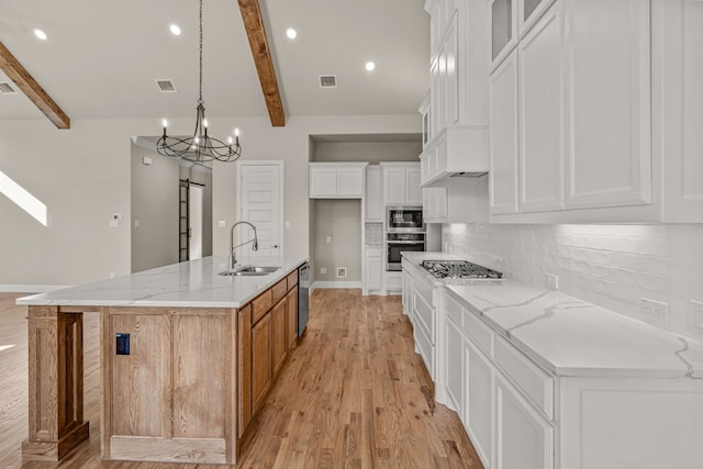 kitchen featuring white cabinetry, sink, a large island, light stone counters, and stainless steel appliances