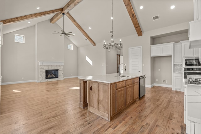 kitchen featuring a large island, light stone countertops, white cabinets, built in microwave, and stainless steel dishwasher