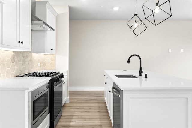 kitchen with hanging light fixtures, gas range oven, light countertops, wall chimney range hood, and a sink