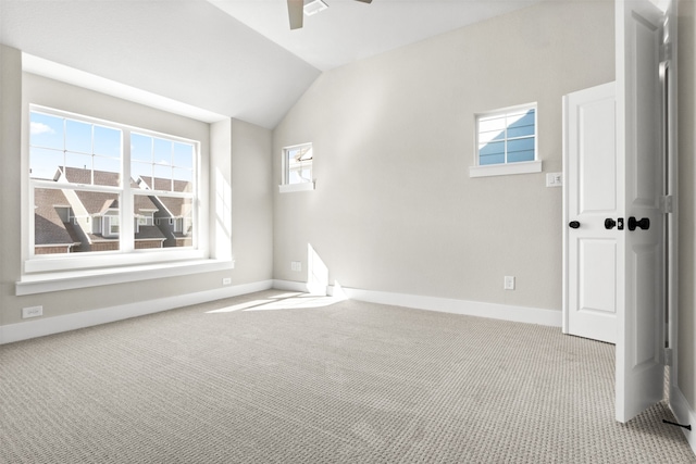 unfurnished room with lofted ceiling, light carpet, a ceiling fan, and baseboards