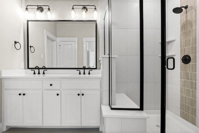 bathroom with double vanity, a shower stall, and a sink