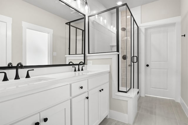 full bathroom featuring double vanity, a stall shower, baseboards, and a sink