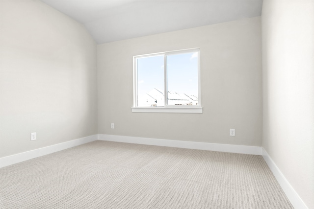 spare room featuring lofted ceiling, carpet, and baseboards