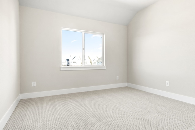 carpeted spare room with baseboards and vaulted ceiling