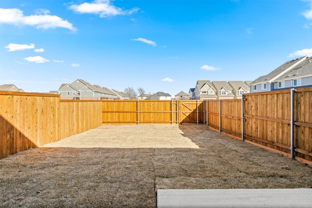 view of yard with a fenced backyard, a residential view, and a gate