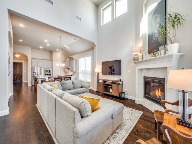 living room featuring a premium fireplace, a towering ceiling, and dark hardwood / wood-style floors