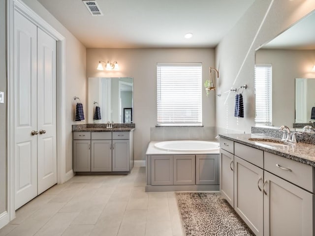 bathroom featuring vanity, a bath, and tile patterned flooring