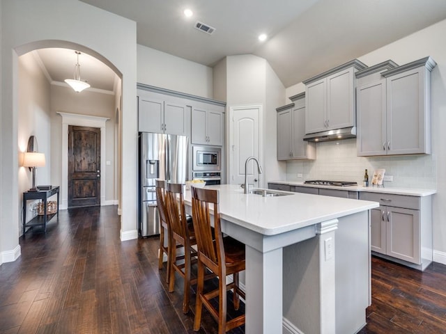 kitchen with decorative light fixtures, gray cabinets, sink, appliances with stainless steel finishes, and an island with sink