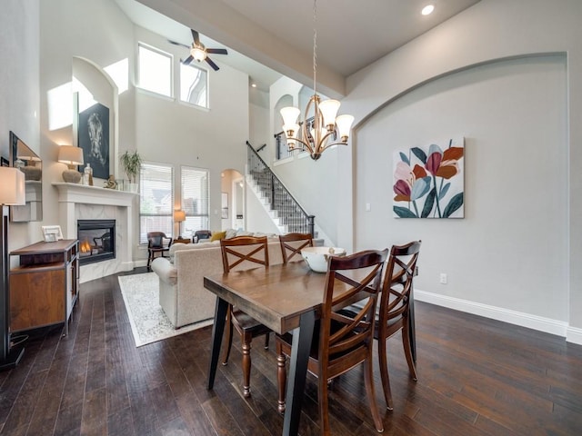 dining room with a high ceiling, dark wood-type flooring, and ceiling fan with notable chandelier