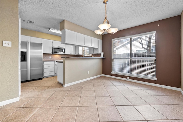 kitchen featuring white cabinetry, decorative light fixtures, appliances with stainless steel finishes, kitchen peninsula, and decorative backsplash