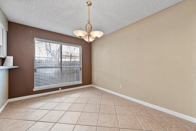 empty room featuring a chandelier, a textured ceiling, and light tile patterned floors