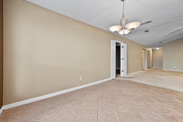 tiled spare room with lofted ceiling, a textured ceiling, and a notable chandelier