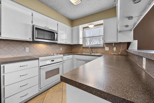 kitchen with white cabinetry, light tile patterned floors, sink, and electric range