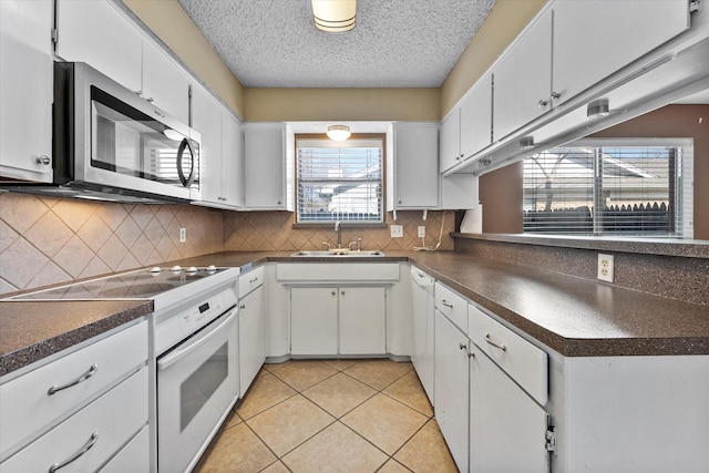 kitchen featuring sink, white appliances, light tile patterned floors, and white cabinets