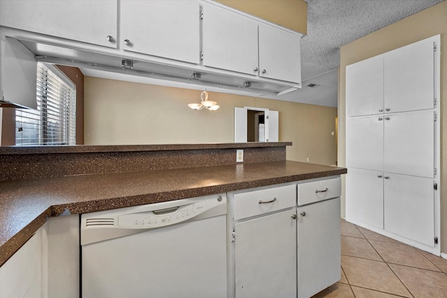 kitchen with white dishwasher, light tile patterned floors, a textured ceiling, and white cabinets