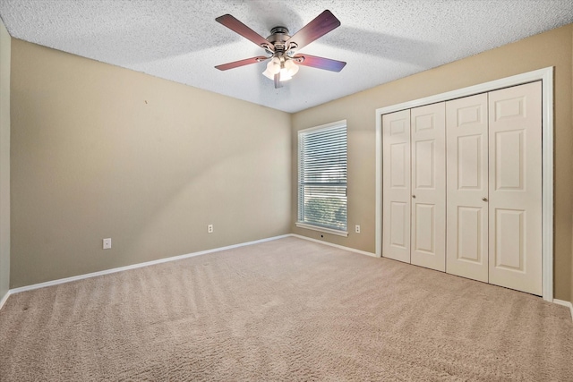 unfurnished bedroom featuring light carpet, a textured ceiling, and ceiling fan