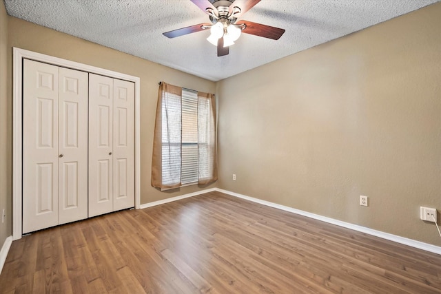 unfurnished bedroom featuring ceiling fan, a closet, a textured ceiling, and light wood-type flooring