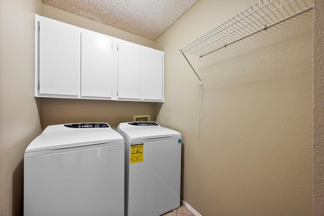 washroom featuring washer and clothes dryer, cabinets, and a textured ceiling