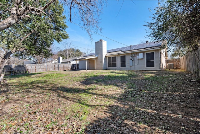 rear view of property with a yard, solar panels, and central air condition unit