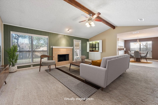 living room with lofted ceiling with beams, plenty of natural light, carpet flooring, and a textured ceiling