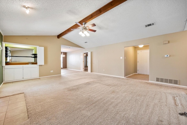 unfurnished living room featuring ceiling fan, vaulted ceiling with beams, light colored carpet, and a textured ceiling