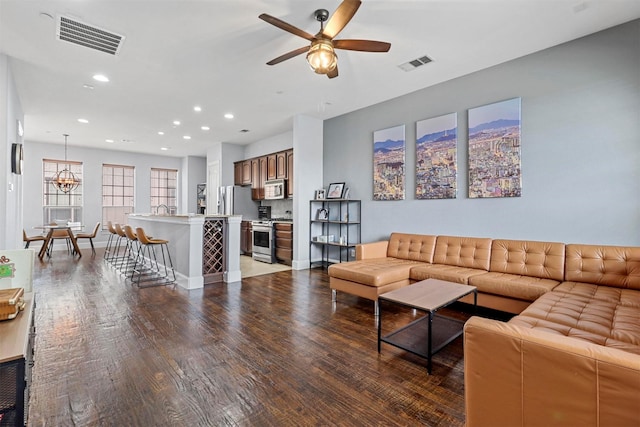 living room featuring dark hardwood / wood-style flooring and ceiling fan with notable chandelier