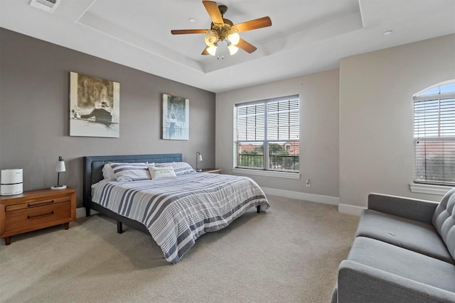 bedroom with ceiling fan, multiple windows, and a raised ceiling