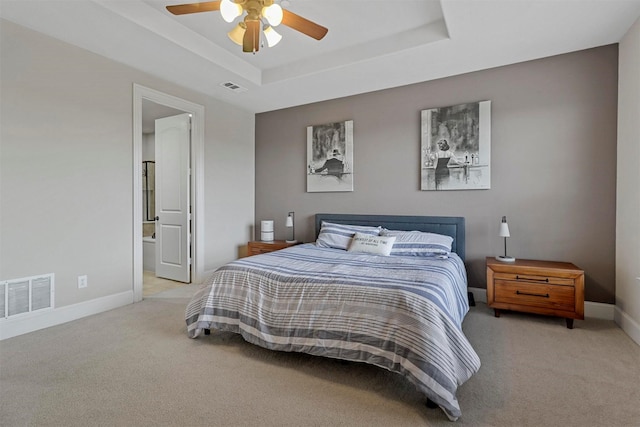 bedroom with ensuite bath, ceiling fan, light carpet, and a tray ceiling