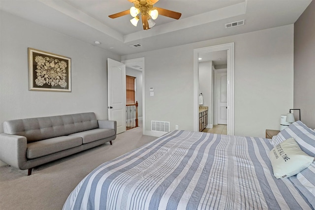 carpeted bedroom with ceiling fan, connected bathroom, and a raised ceiling