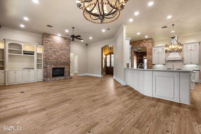 kitchen with decorative light fixtures, ceiling fan, a fireplace, crown molding, and white cabinetry