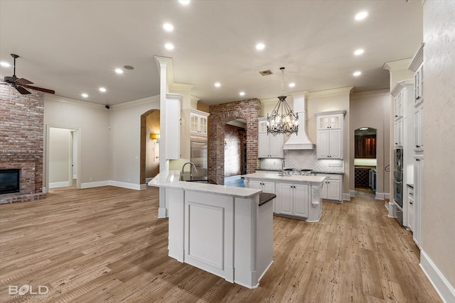 kitchen featuring decorative light fixtures, a center island, crown molding, white cabinetry, and ceiling fan with notable chandelier