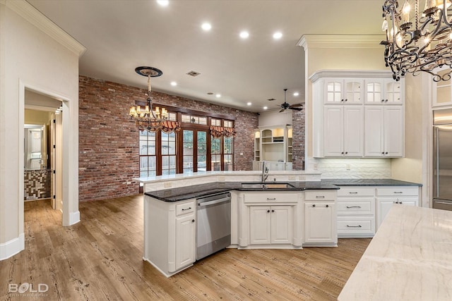 kitchen with ceiling fan with notable chandelier, brick wall, decorative light fixtures, stainless steel appliances, and dark stone counters