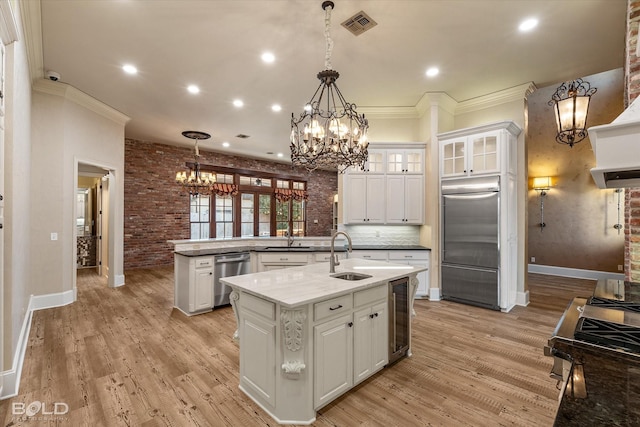 kitchen featuring brick wall, white cabinets, appliances with stainless steel finishes, and sink