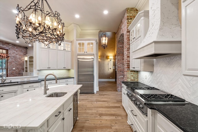 kitchen featuring appliances with stainless steel finishes, dark stone counters, tasteful backsplash, sink, and custom range hood