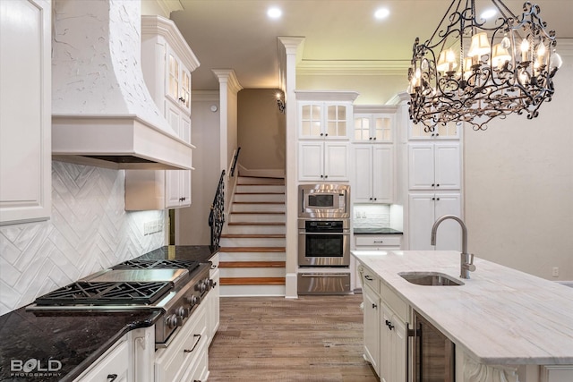 kitchen featuring white cabinetry, appliances with stainless steel finishes, backsplash, dark stone counters, and sink