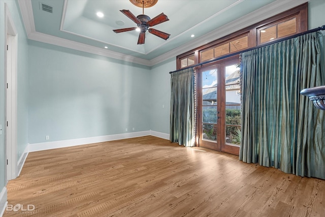 spare room with french doors, light hardwood / wood-style floors, ornamental molding, a raised ceiling, and ceiling fan