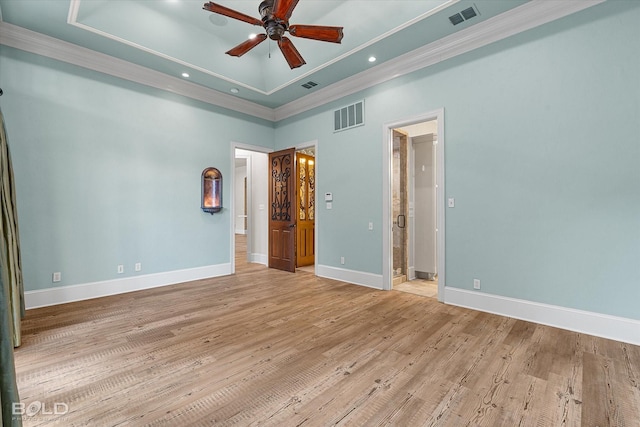 unfurnished bedroom featuring a tray ceiling, ornamental molding, light wood-type flooring, ceiling fan, and ensuite bathroom