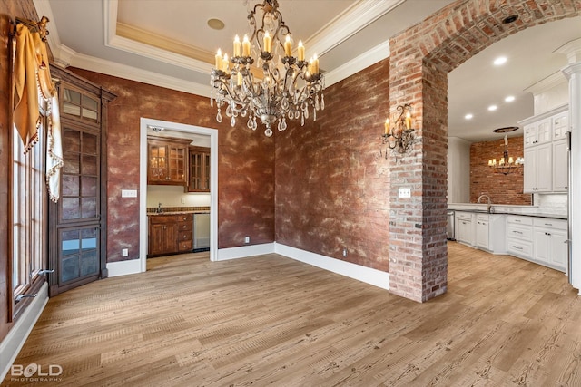 unfurnished dining area with a tray ceiling, sink, crown molding, and light hardwood / wood-style flooring