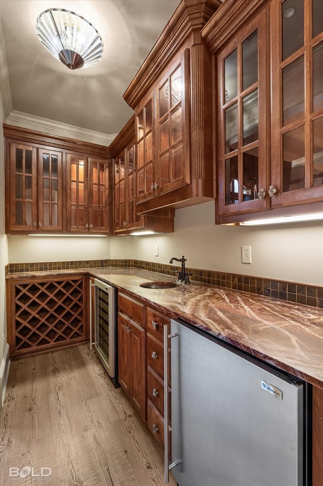 bar with wine cooler, sink, crown molding, light hardwood / wood-style flooring, and light stone countertops