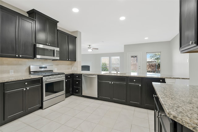 kitchen featuring ceiling fan, appliances with stainless steel finishes, tasteful backsplash, and light stone counters