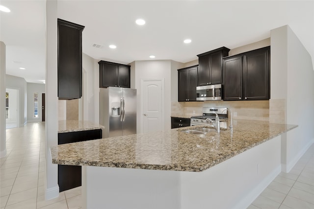 kitchen featuring light tile patterned floors, kitchen peninsula, appliances with stainless steel finishes, and light stone counters