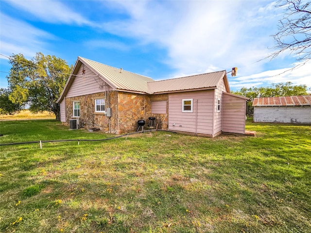 rear view of house with central AC unit and a lawn