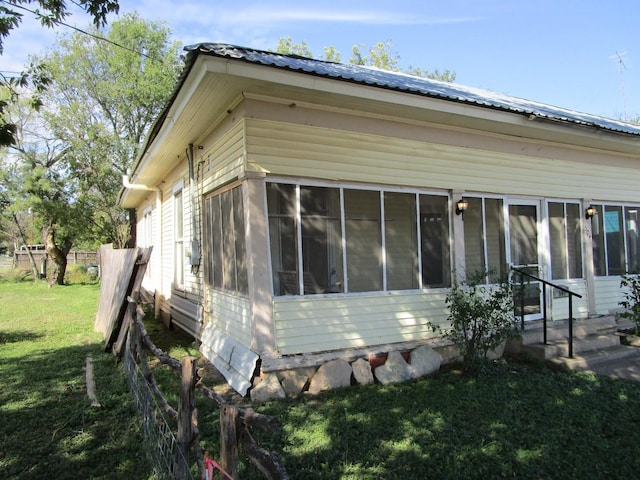 view of home's exterior featuring a sunroom and a yard