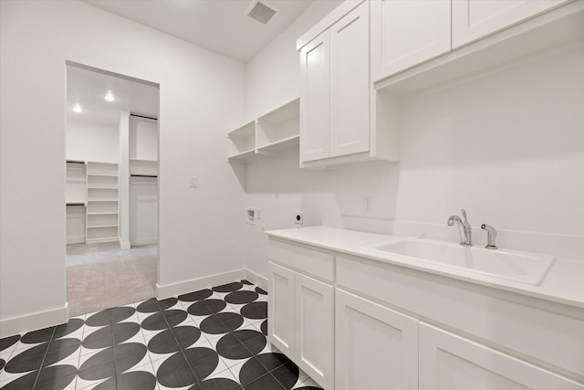 laundry area featuring electric dryer hookup, sink, washer hookup, dark carpet, and cabinets